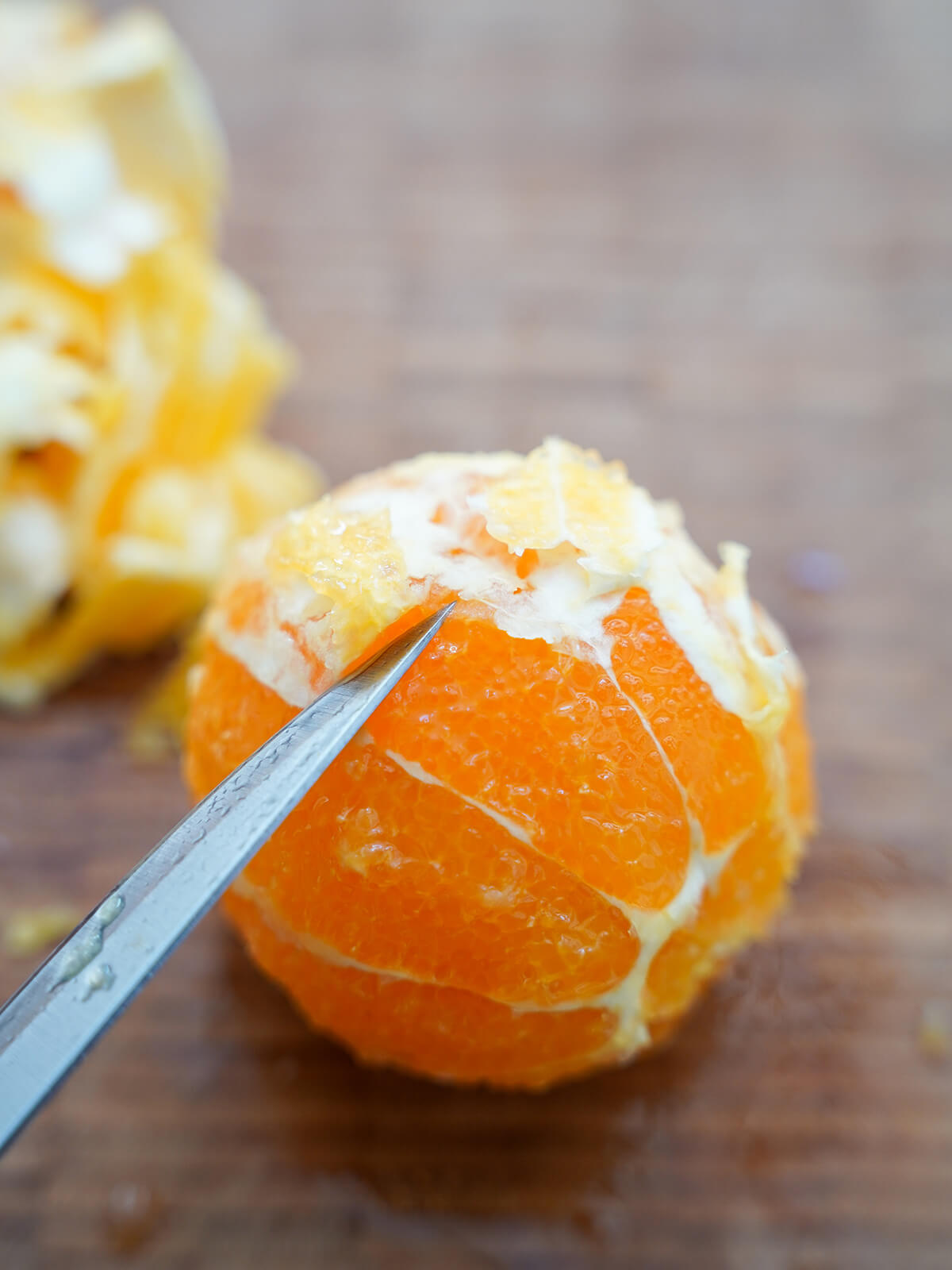 using knife to peel white membrane from an orange.