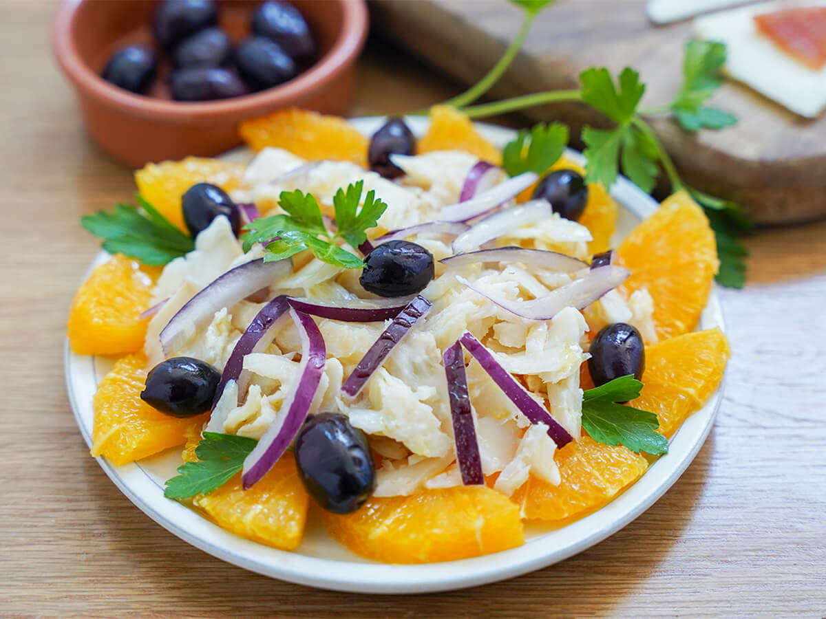 plate of remojon, salt cod orange salad topped with olives and parsley.