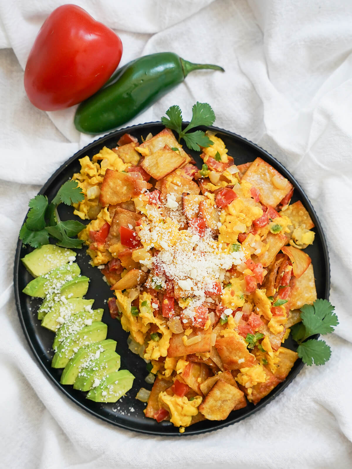 plate of Mexican migas from overhead with tomato and jalapeno above plate.