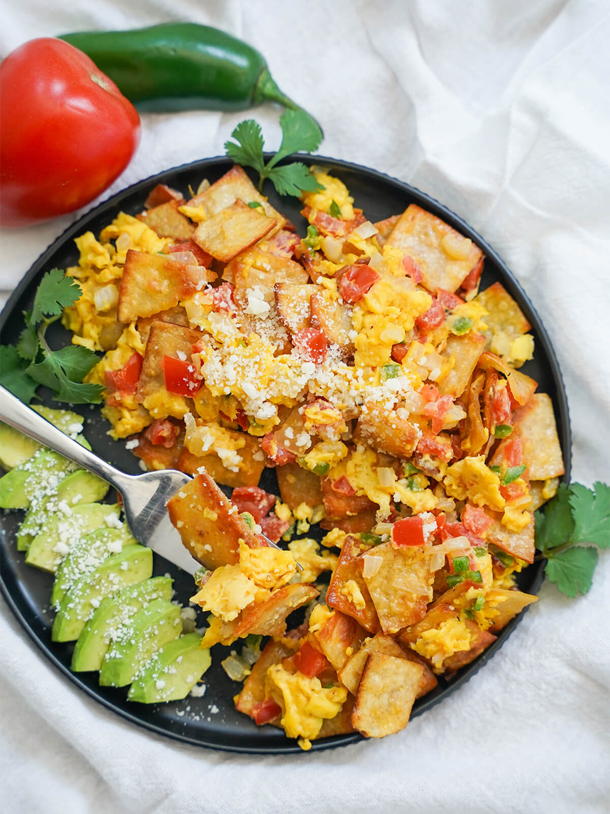 plate of Mexican migas with fork with som eof mix resting on top.