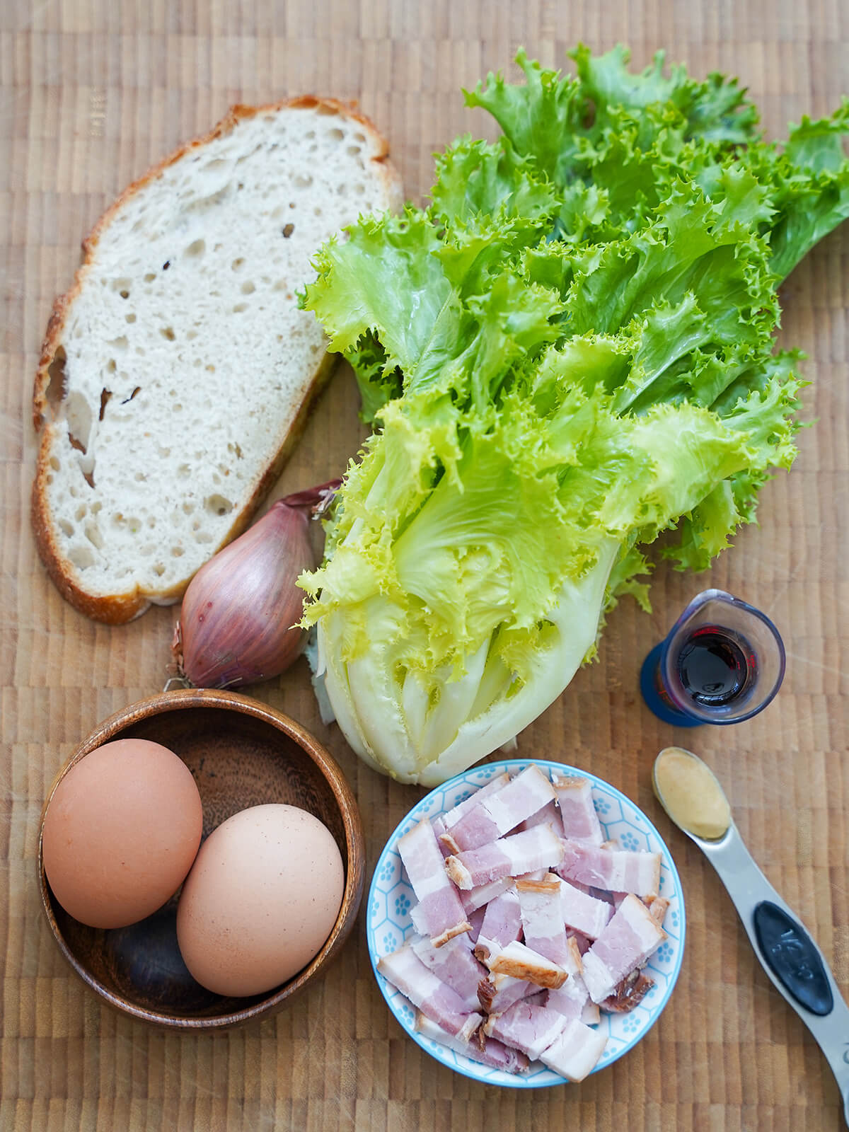 bunch of frisee, slice of bread, cut bacon, eggs, shallot.