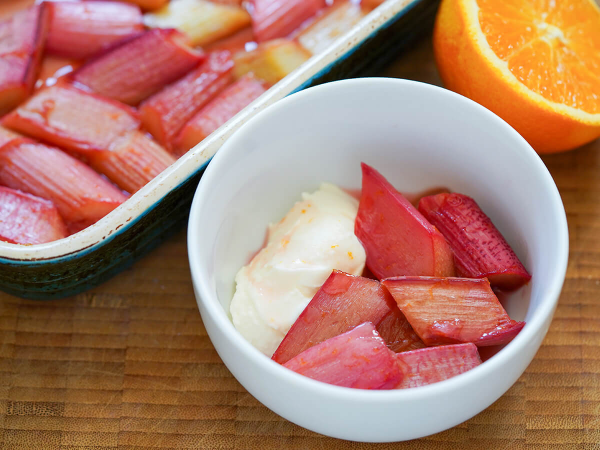 bowl of roasted rhubarb and creme fraiche with more rhubarb in dish behind.