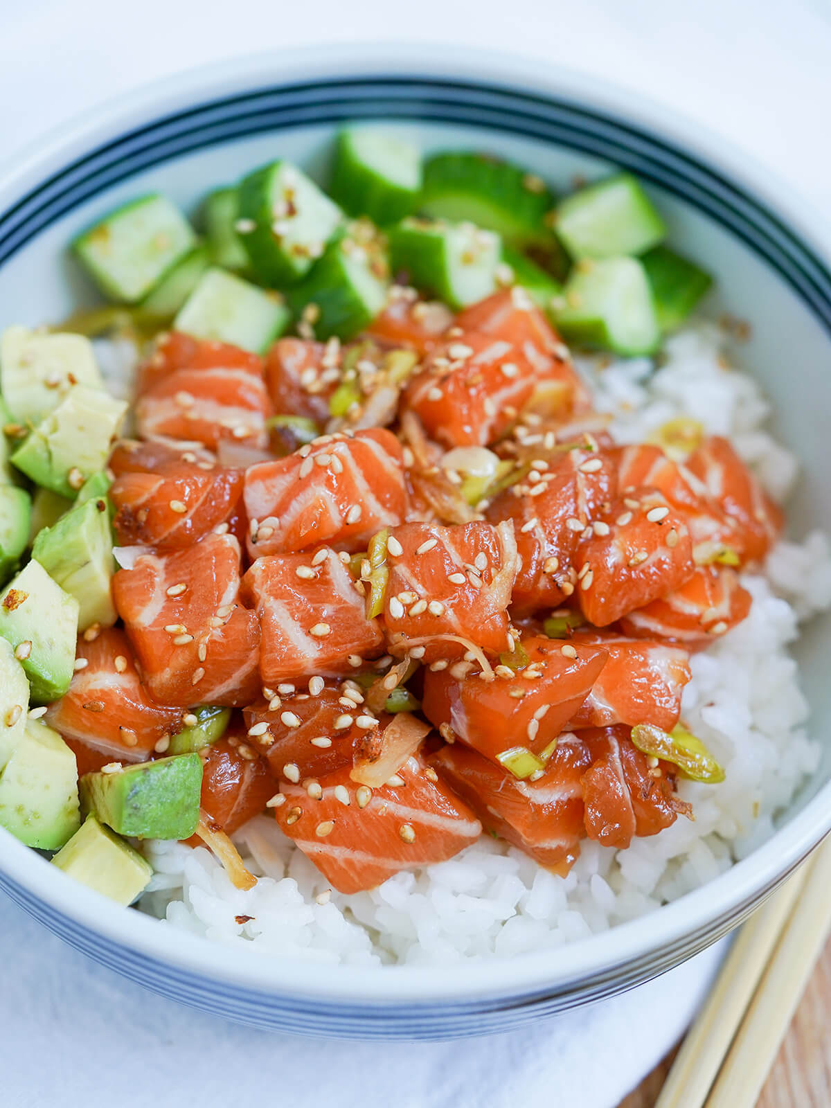 close view of salmon poke bowl with salmon, rice, avocado and cucumber.