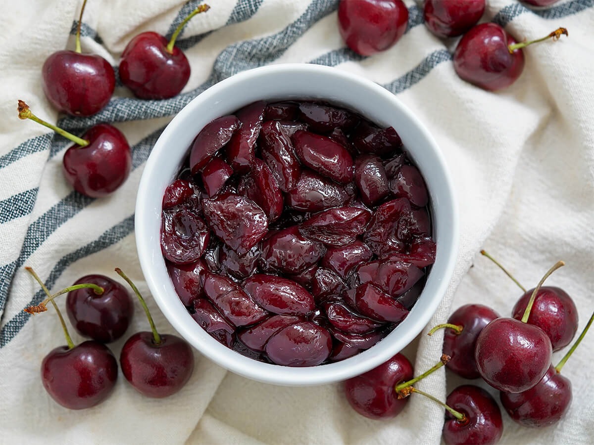 bowl of cherry compote with cherries either side.