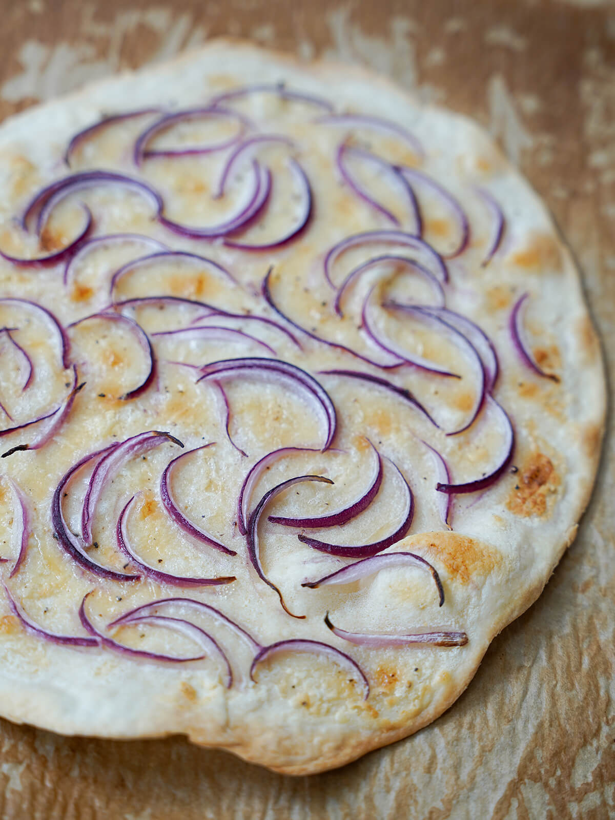 baked base layer of smoked salmon pizza cooked pizza base with slightly browned edges and cooked onion slices on top.