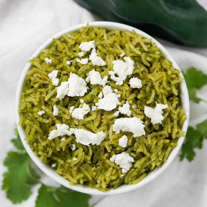 close overhead view of bowl of arroz verde Mexican green rice topped with cheese.