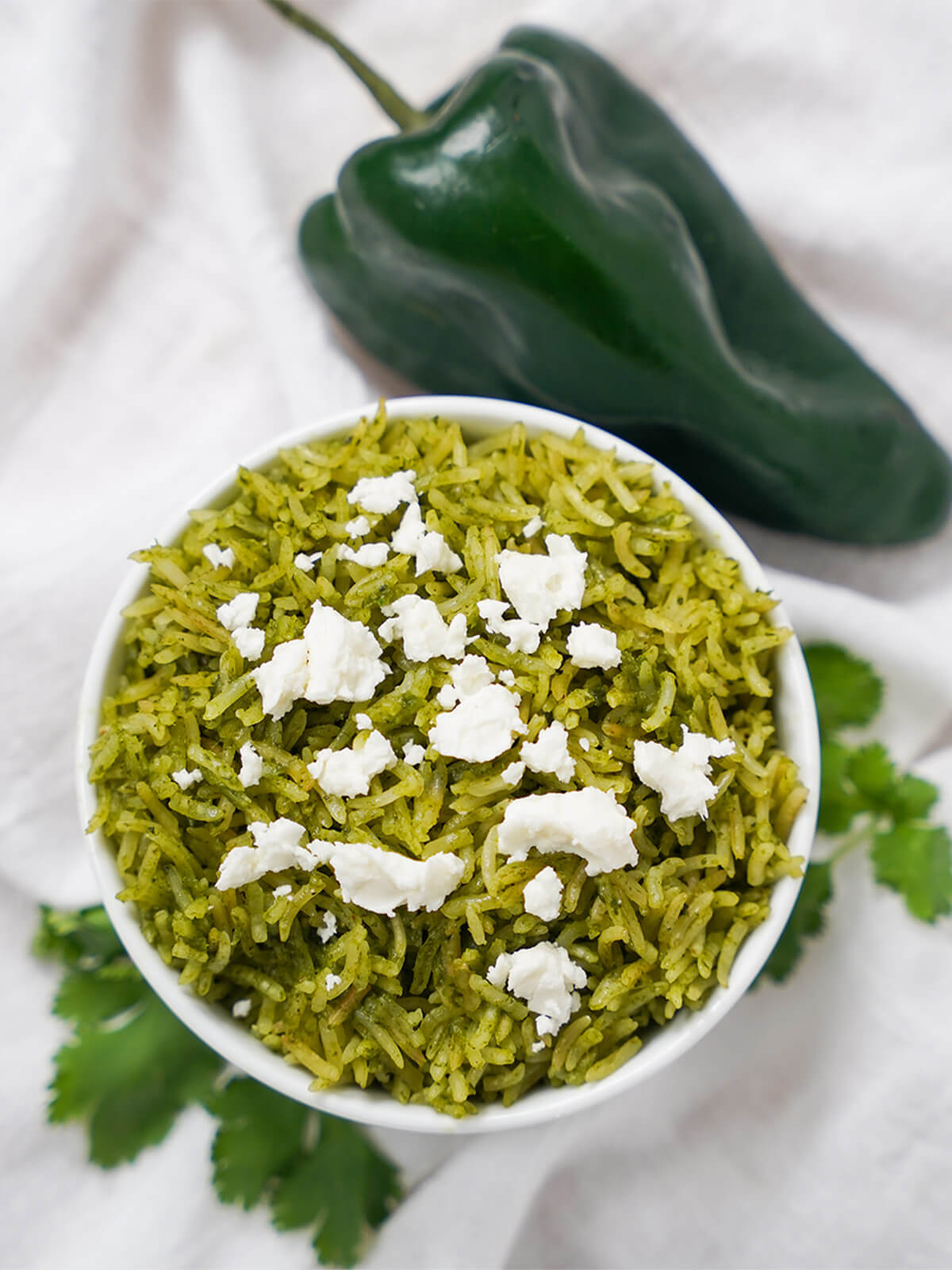bowl of arroz verde Mexican green rice with poblano pepper above bowl.