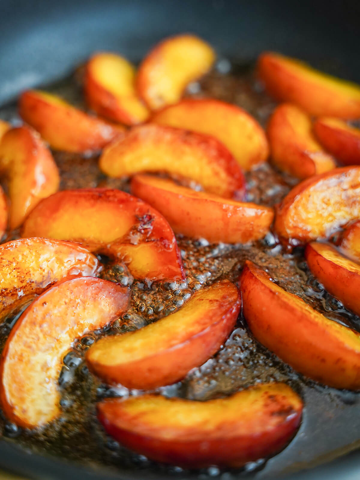 cooking peaches with bubbling caramel around slices.