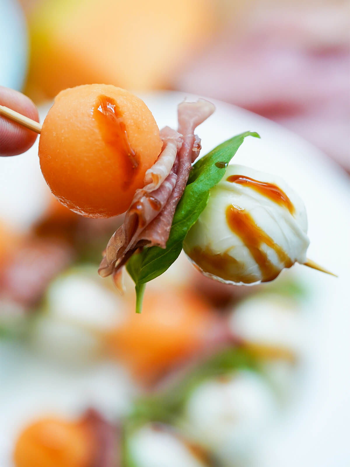 holding a melon and prosciutto skewer