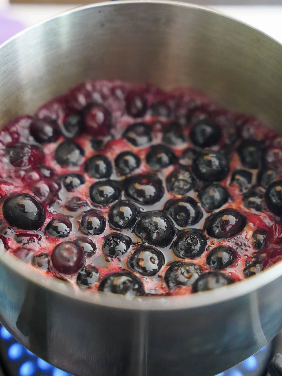 blueberries simmering in saucepan with purple syrupy mixture bubbling around berries.