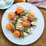 close overhead view of plate of melon and prosciutto skewers.