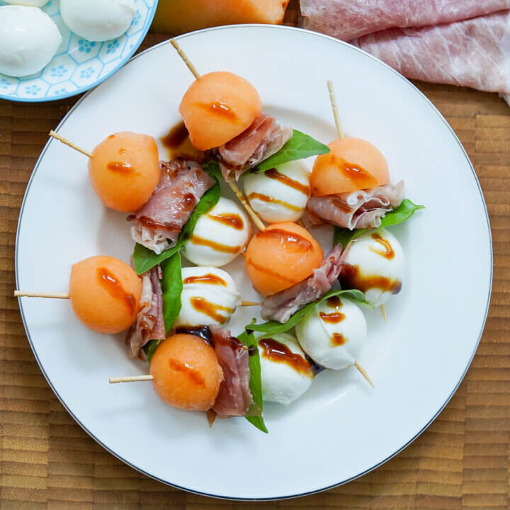 close overhead view of plate of melon and prosciutto skewers.