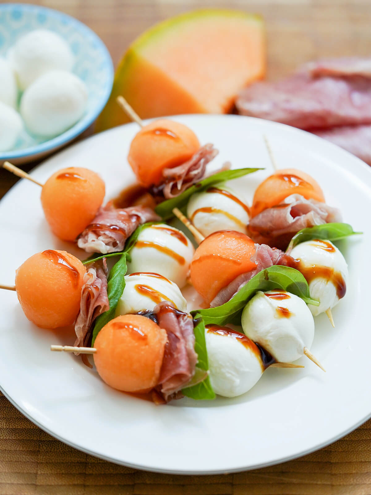 plate of melon and prosciutto skewers from side.