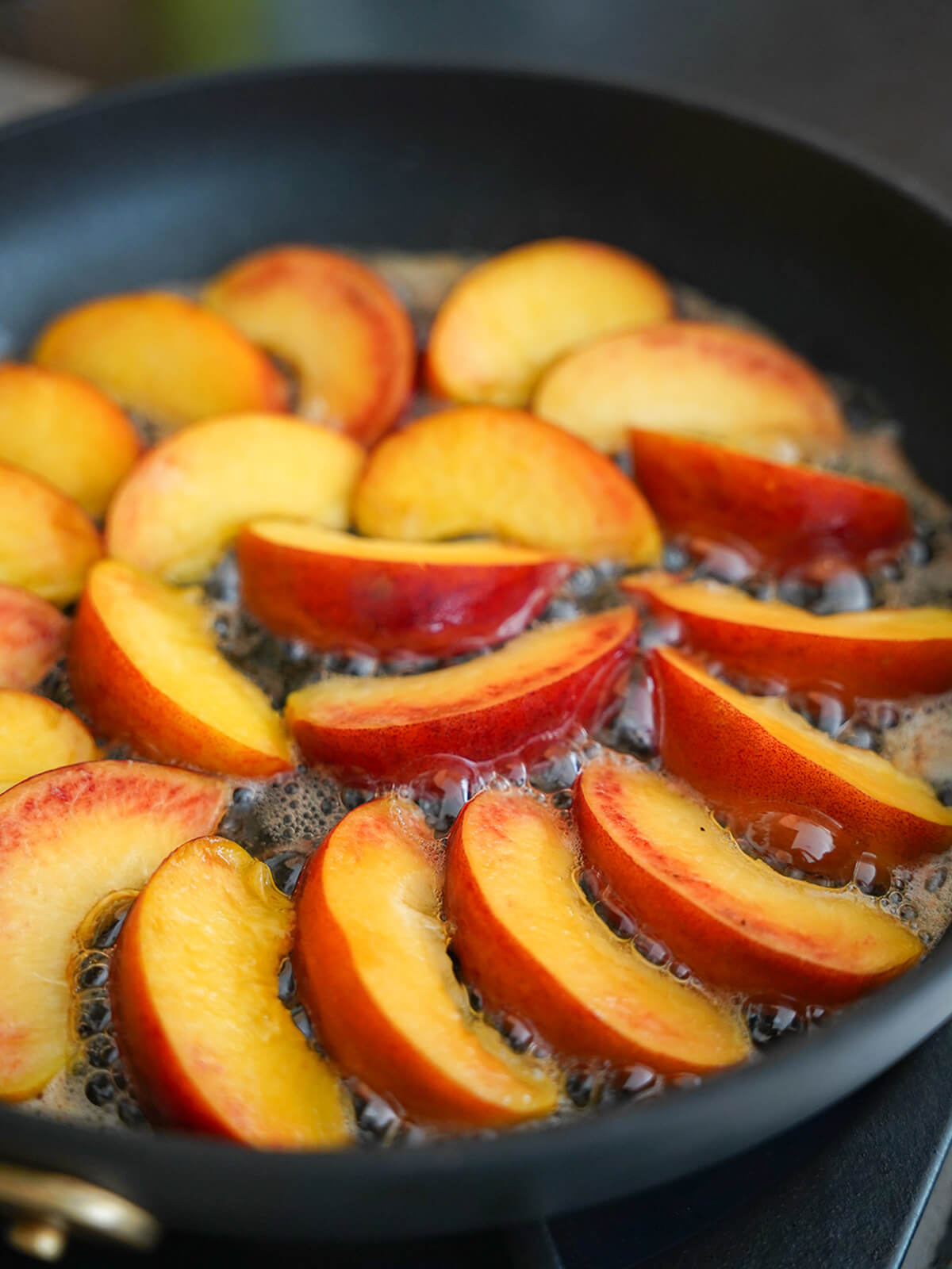 start of cooking peach slices in butter in skillet.