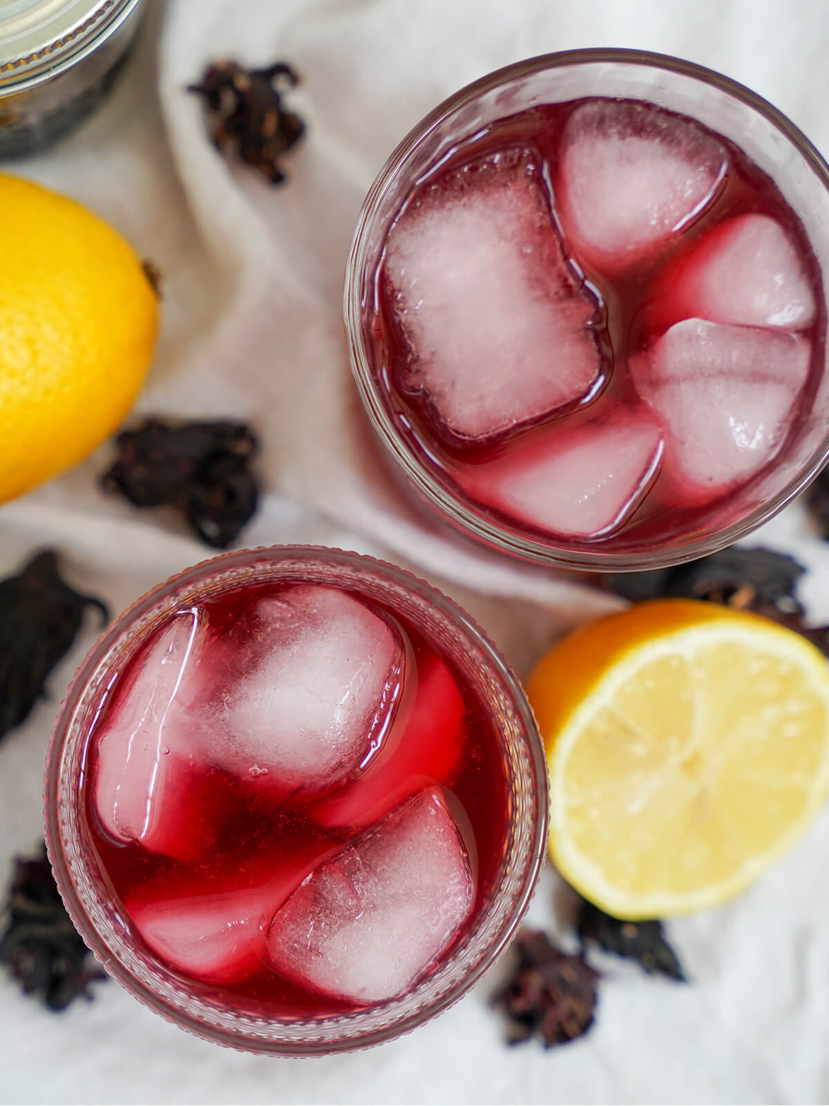 two glasses of hibiscus lemonade with ice in glasses from overhead.
