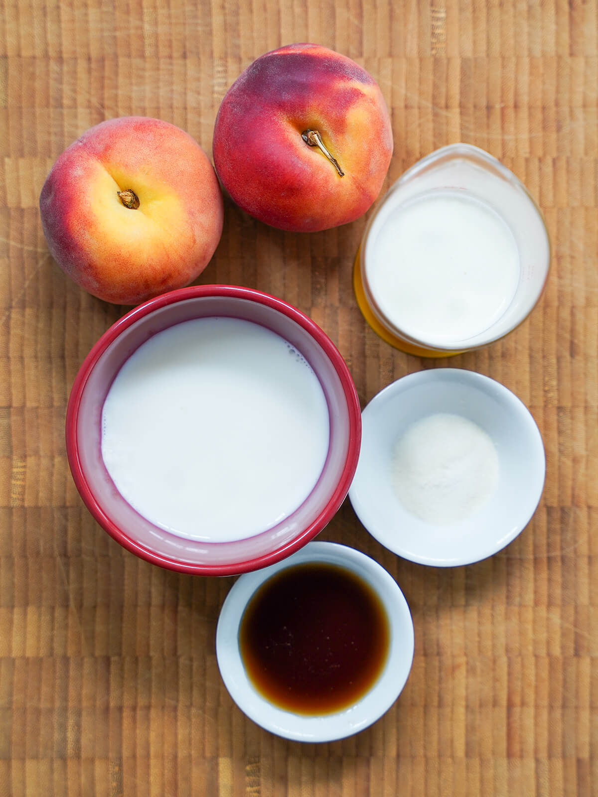 bowl of cream, measure of milk, peaches and small dishes with maple syrup and gelatin.