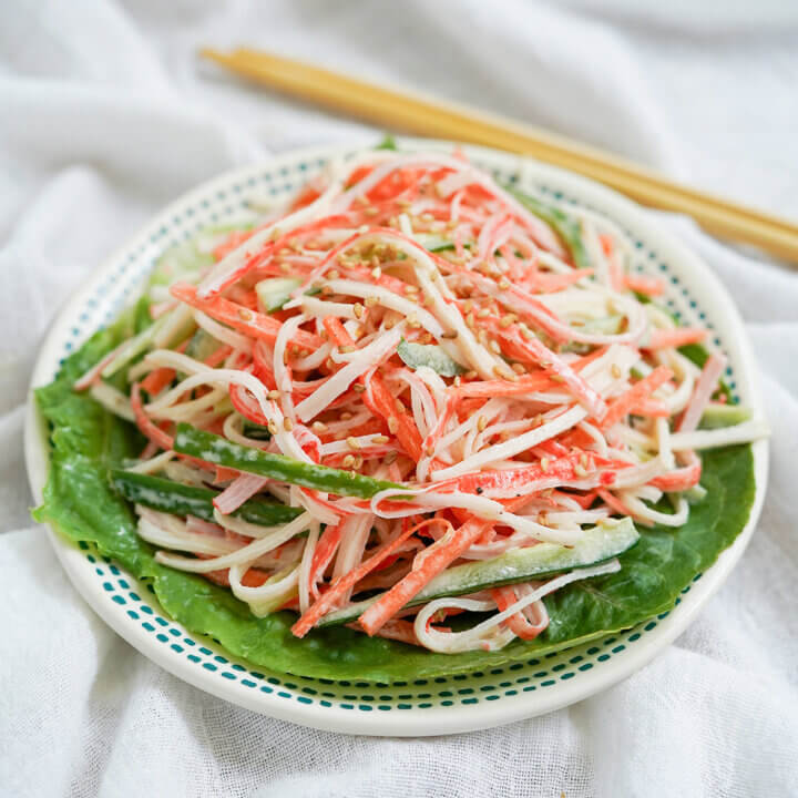 plate of kani salad from side with chopsticks behind plate.