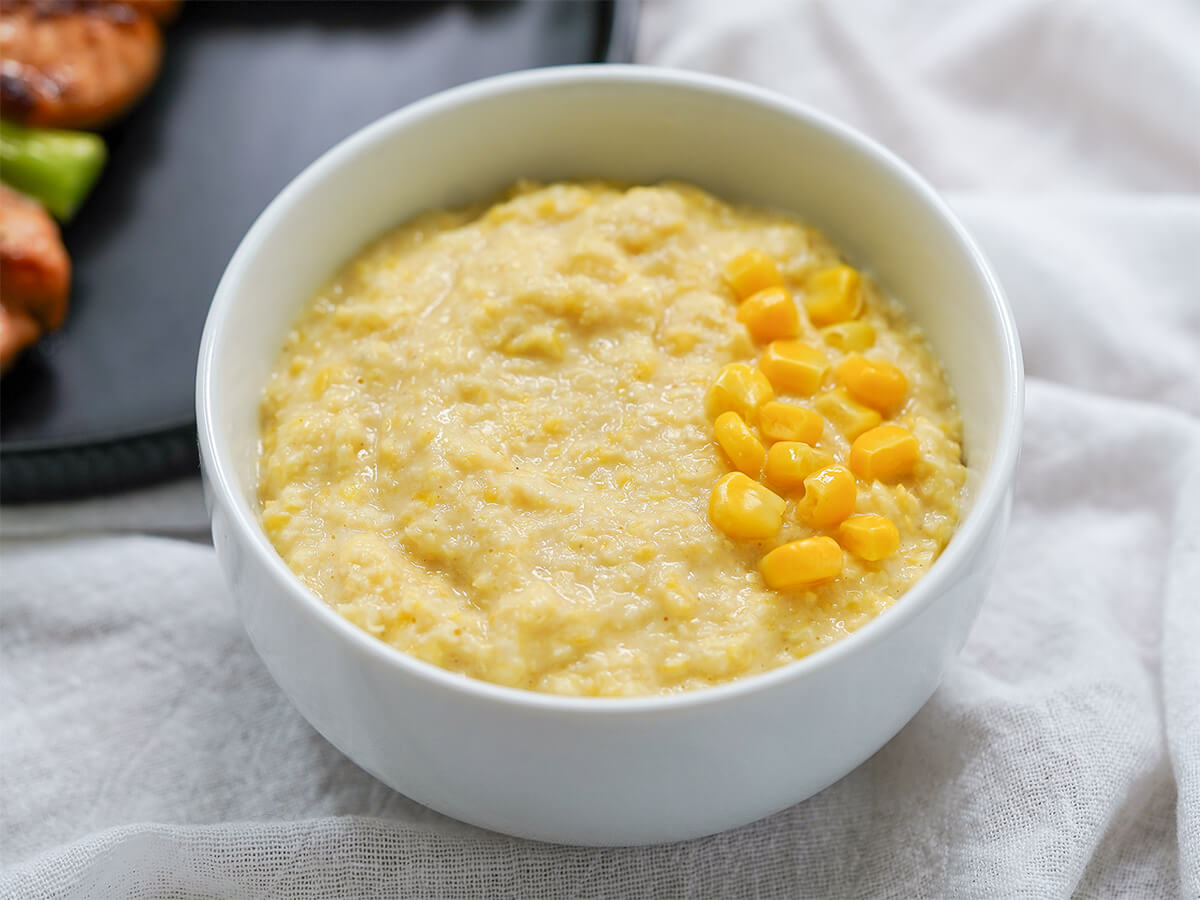 bowl of corn puree topped with pieces of corn.