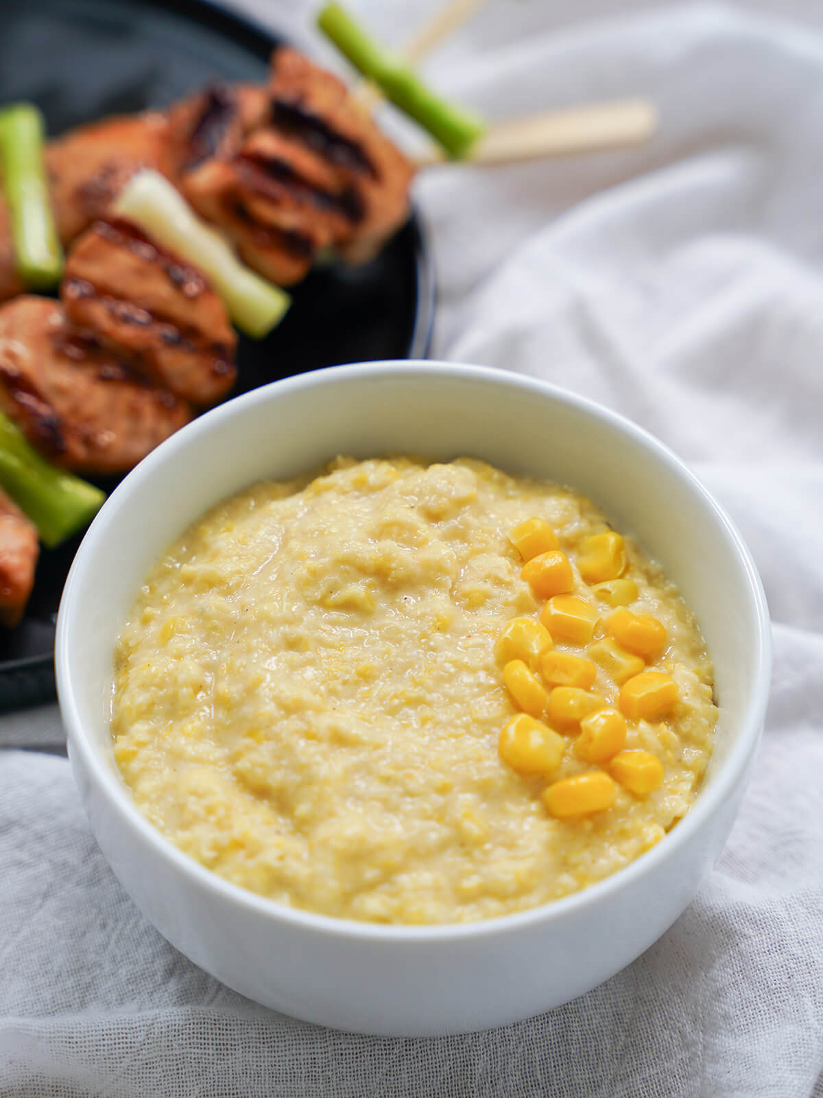 bowl of corn puree in front of plate of salmon teriyaki skewers.
