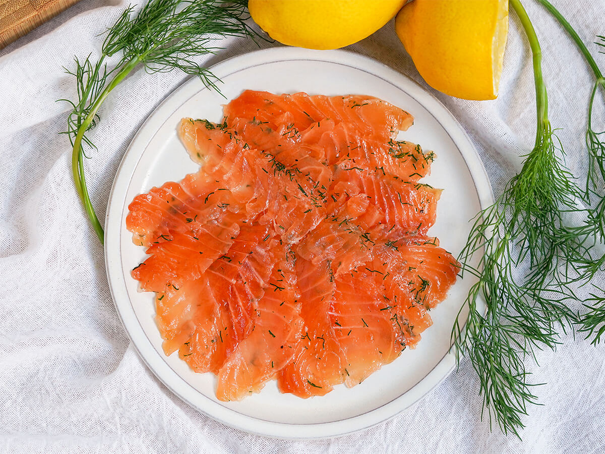 slices of salmon gravlax on plate with dill on either side.