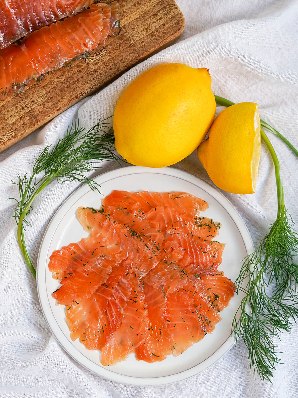 plate of salmon gravlax with dill either side and lemon above.