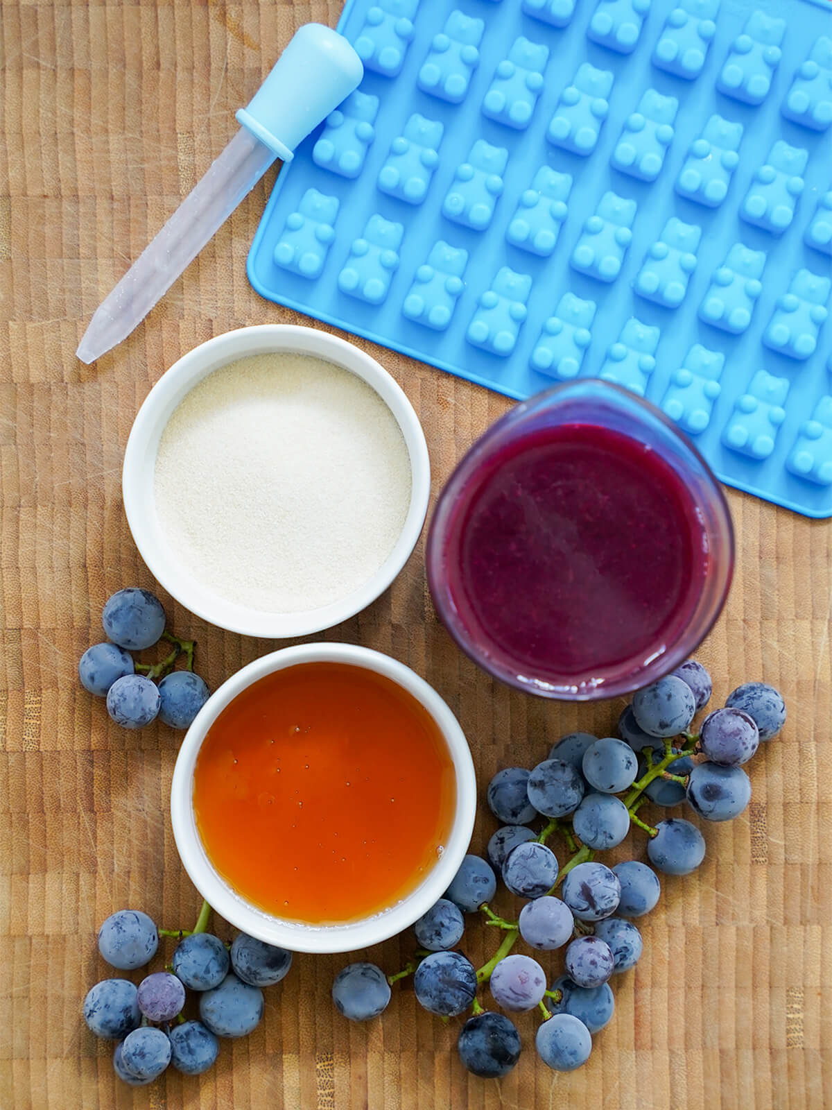 dishes with gelatin, grape juice, honey and grapes below, bear mould and dropped above.