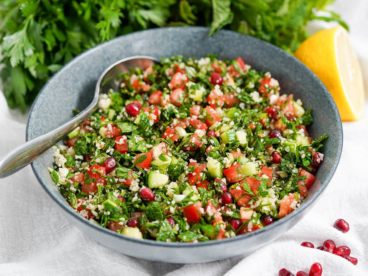 pomegranate tabbouleh bowl of tabbouleh with pomegranate with a spoon resting in back of bowl.