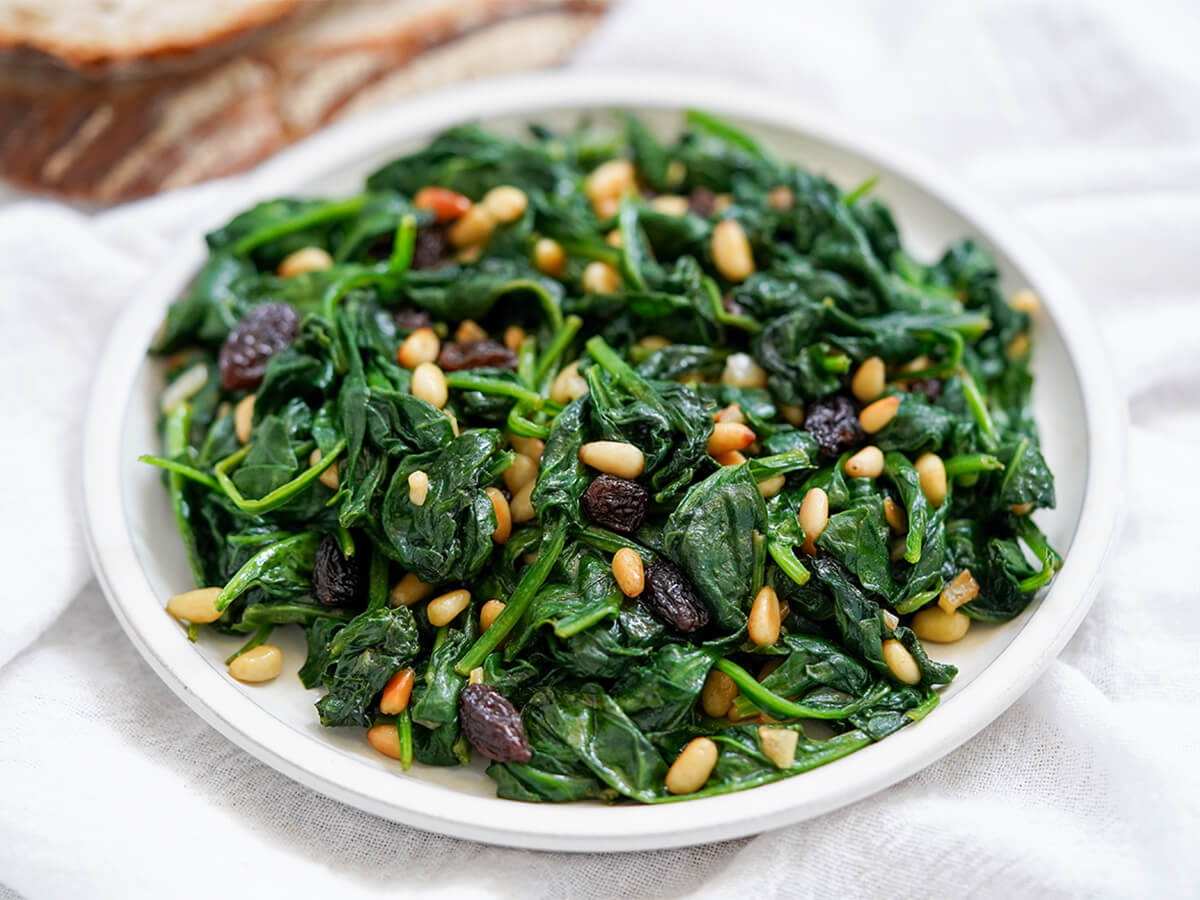 close up view of plate of Catalan spinach with pine nuts and raisins.
