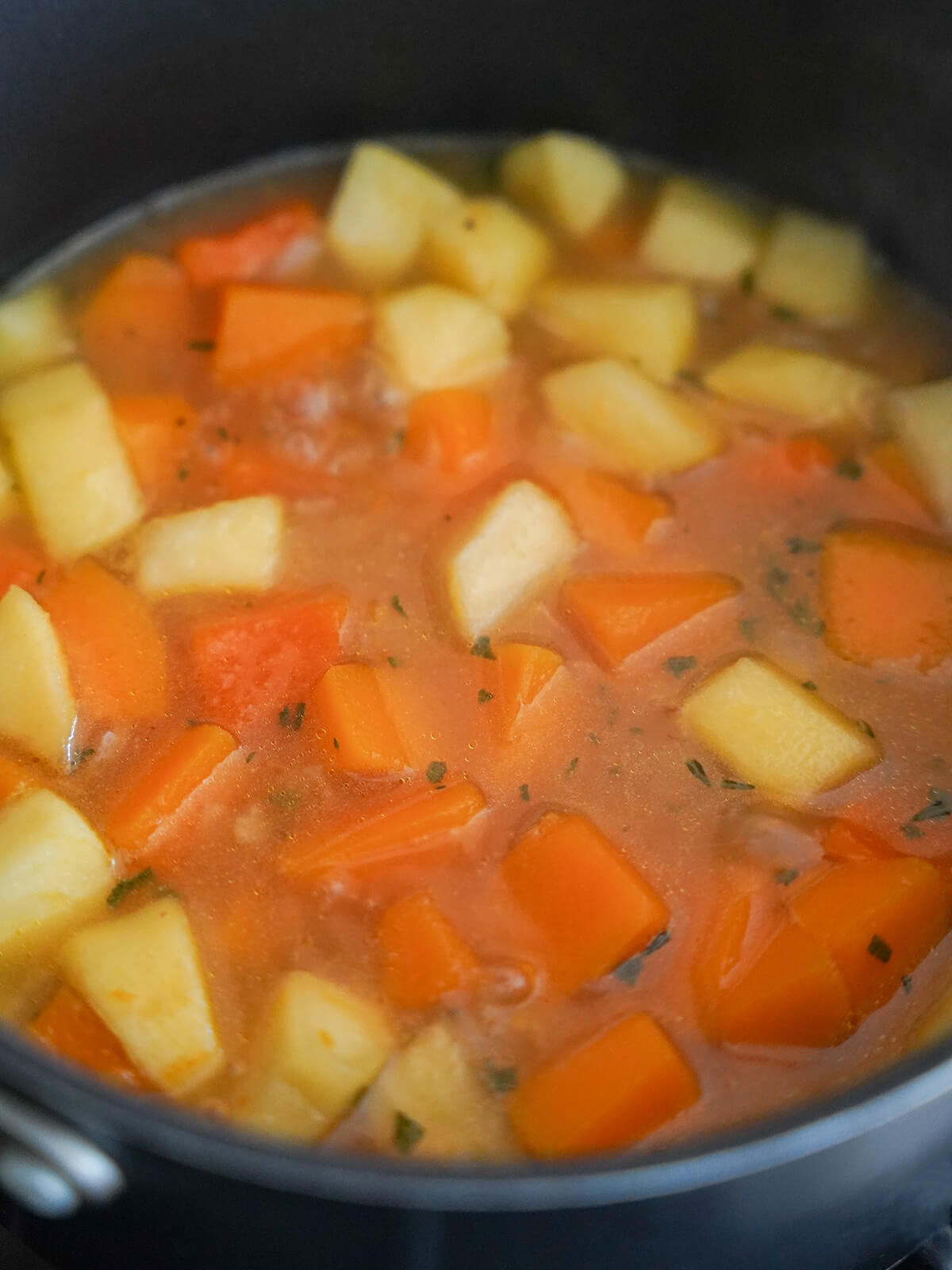 making butternut squash apple soup chunks of squash and apple in pot with stock.