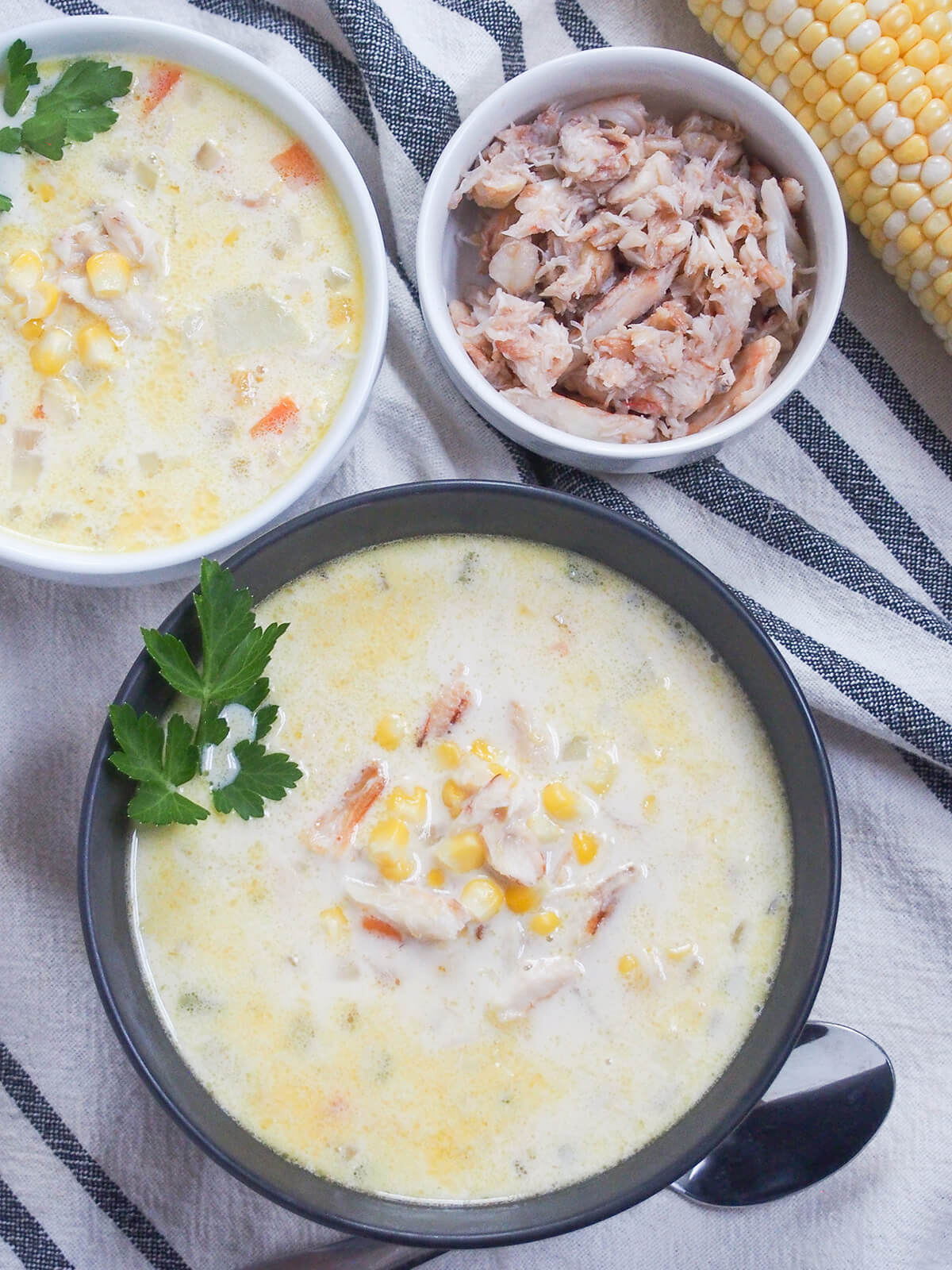 overhead view of bowls of crab and corn chowder with small bowl of crab above