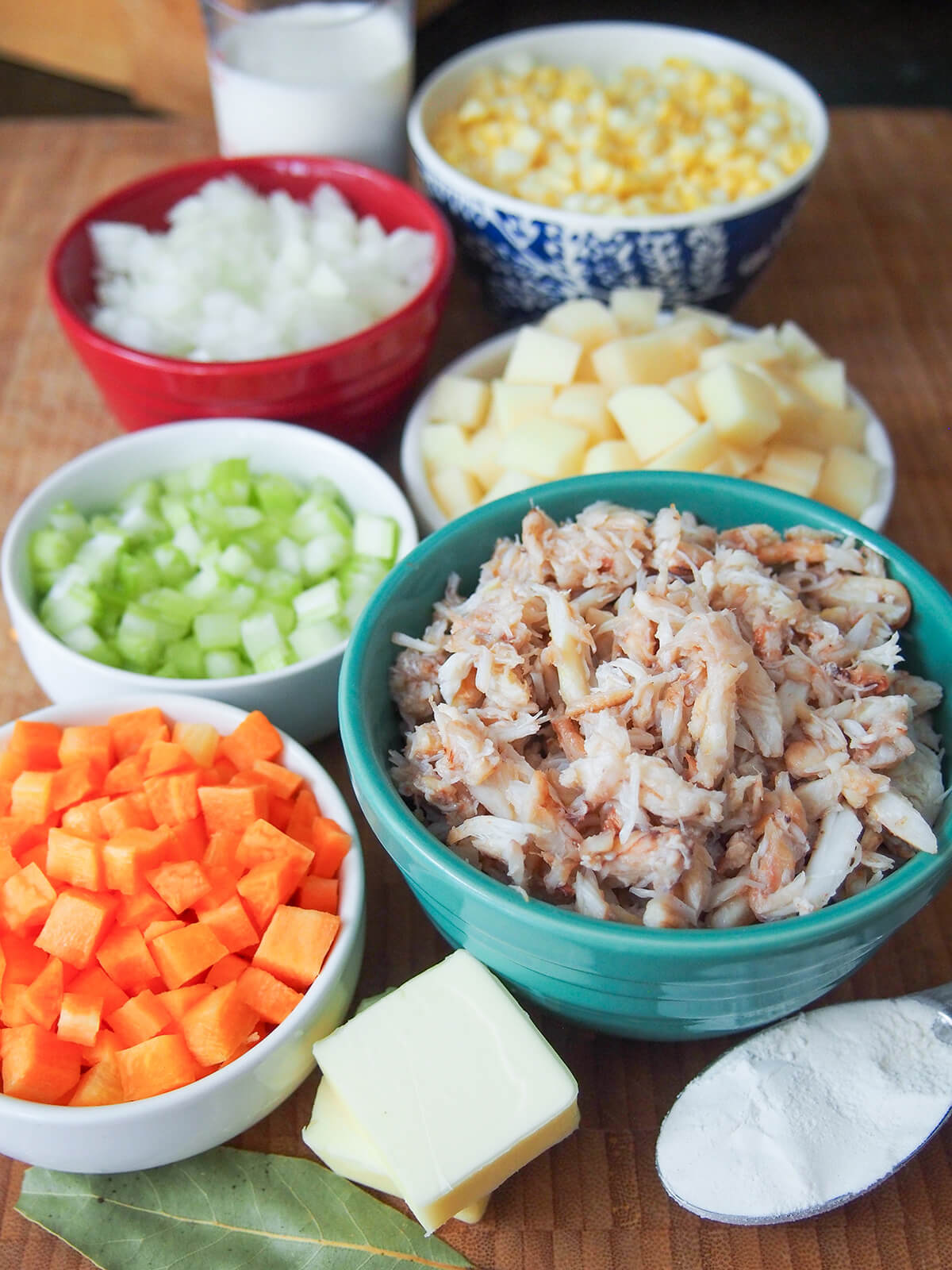 bowls of diced vegetables and crab with cream behind and chunks of butter and spoon of flour in front.