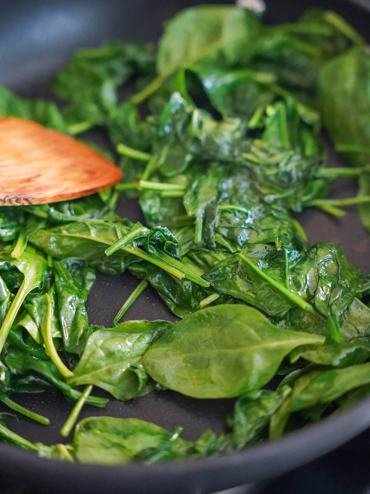 wilting down spinach ni skillet.