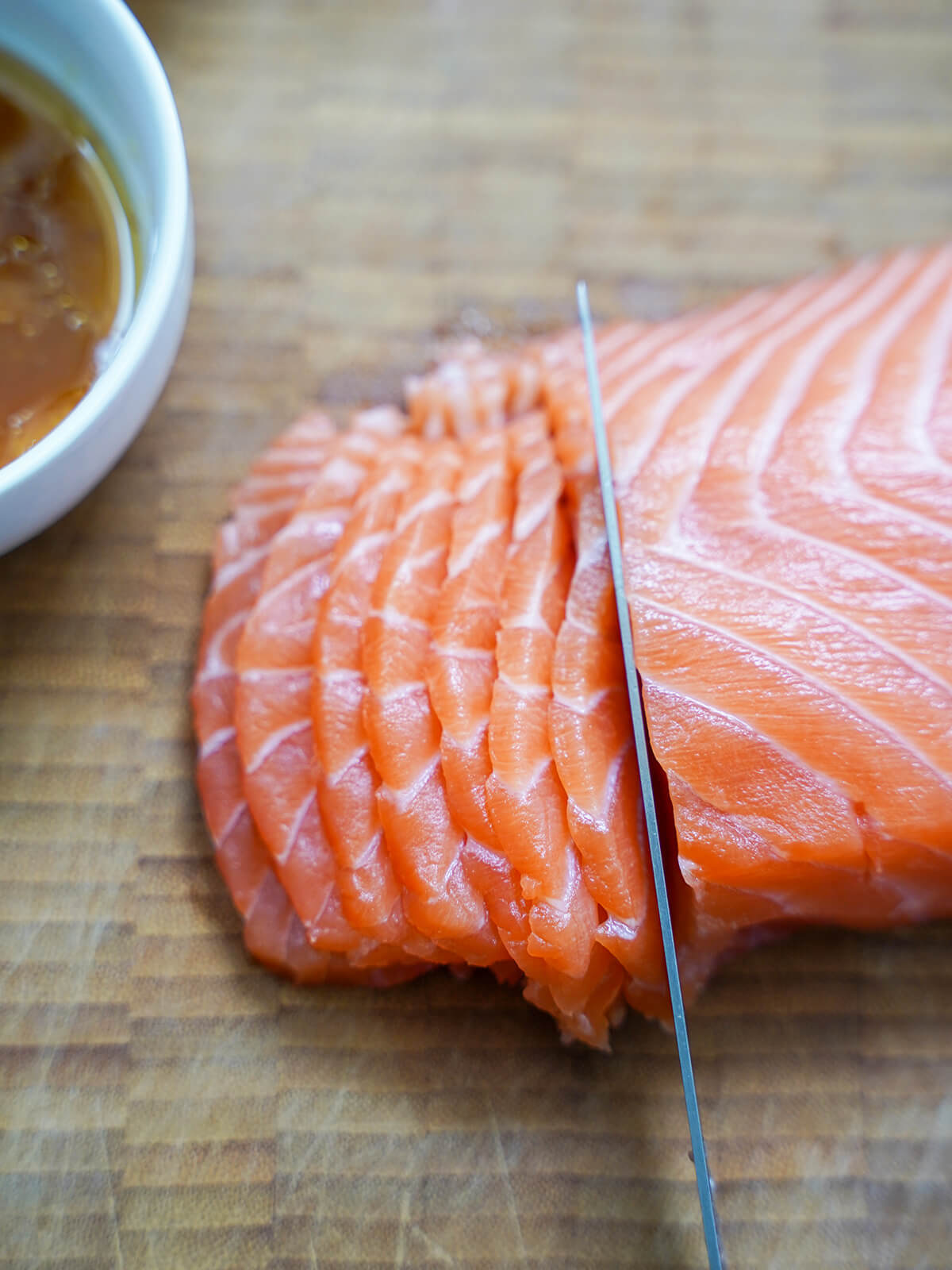 cutting chunk of salmon into thin slices.