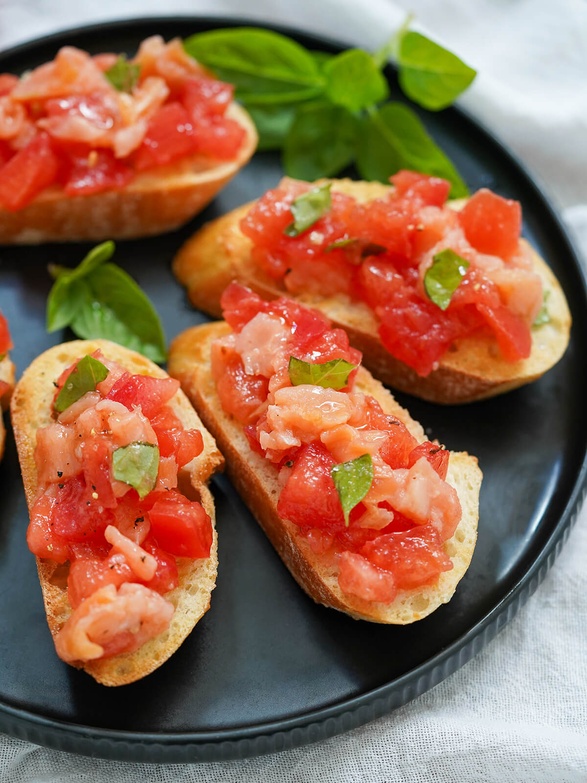 pieces of smoked salmon bruschetta on plate with basil in background.