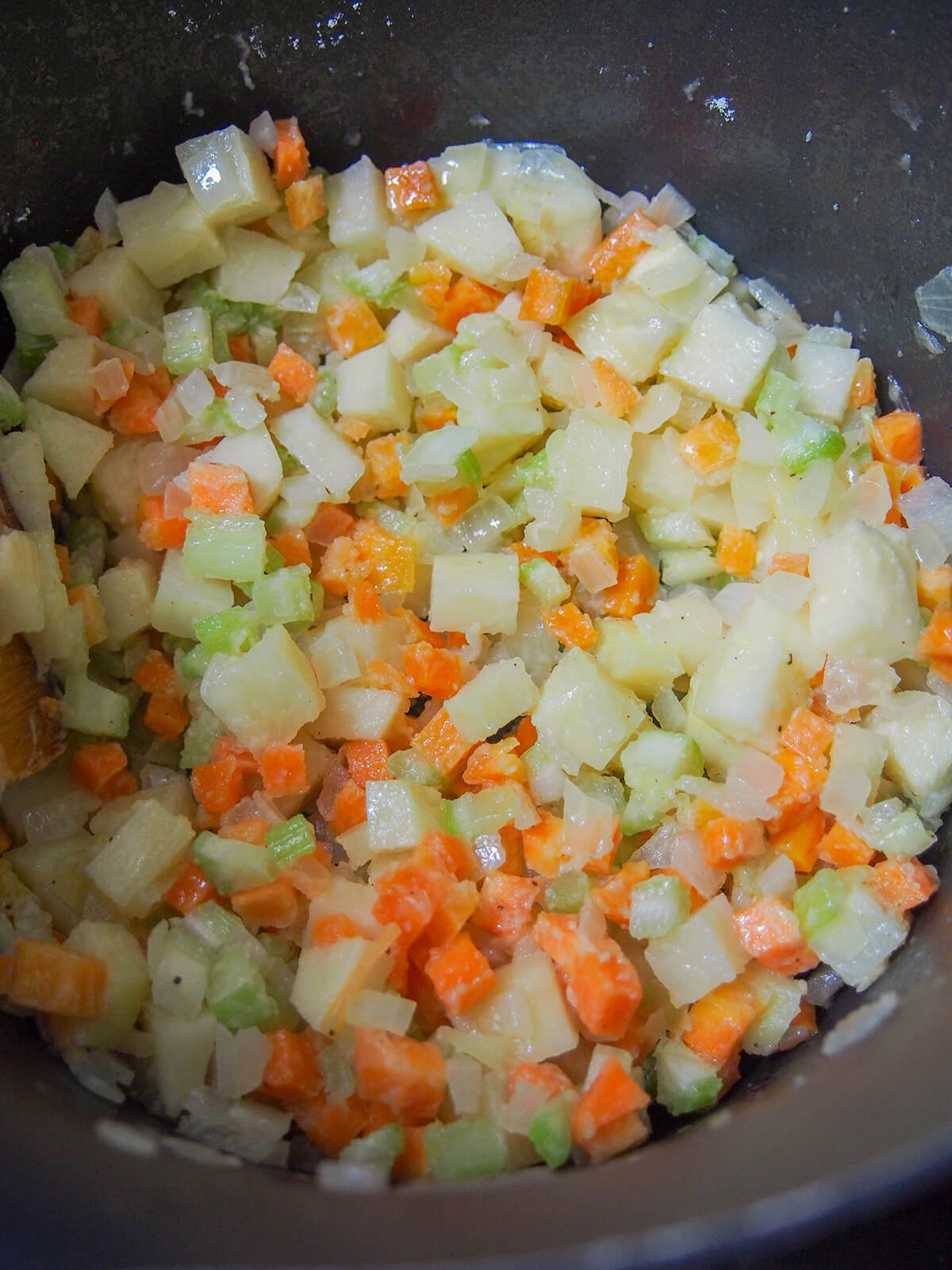 part cooked diced potato, carrot, onion and celery in pot with flour added giving slight coating.