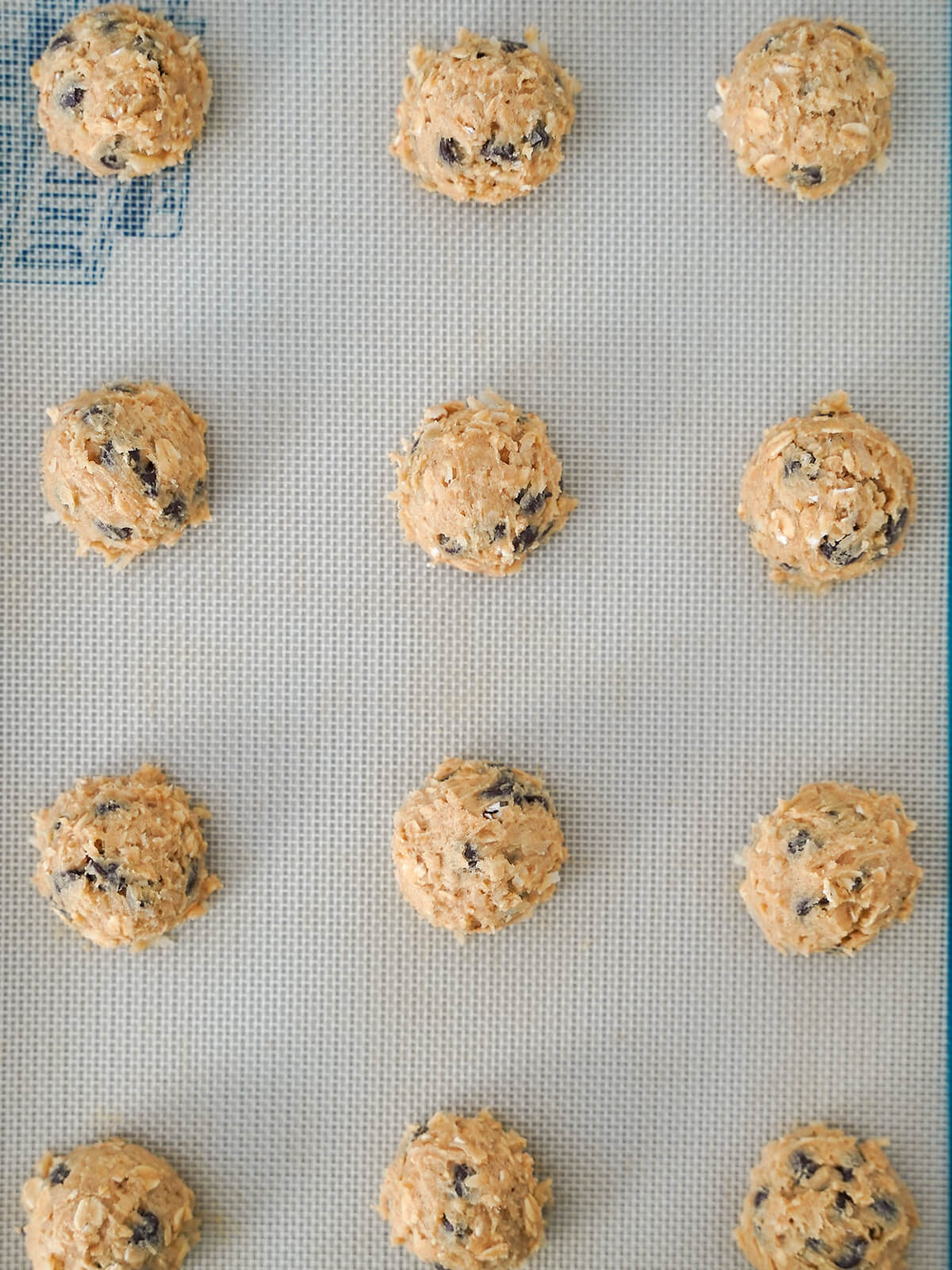 balls of cookie dough on a lined baking sheet from overhead.
