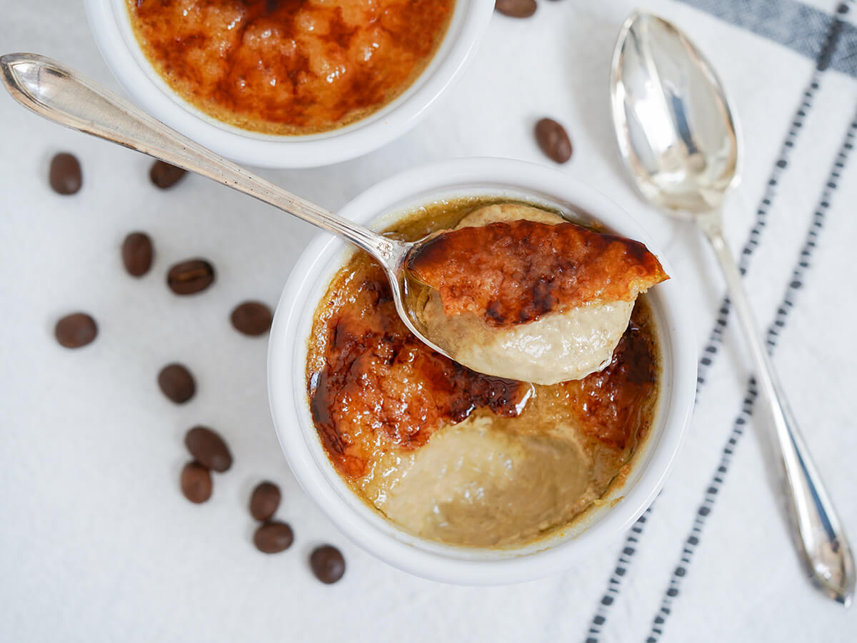 overhead view of a spoonful of coffee creme brulee sitting on top of sugar crust of rest in dish.