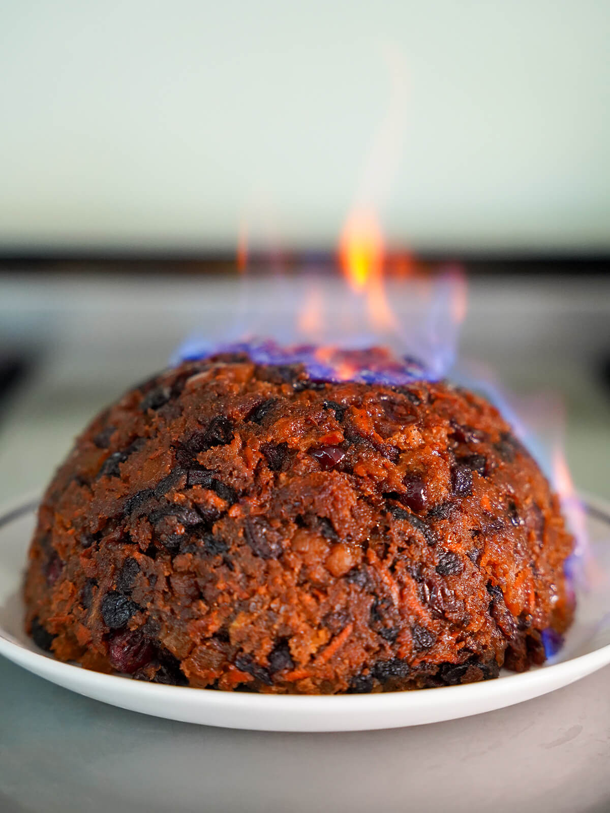 Christmas pudding with flames on top and side from brandy lit on it.