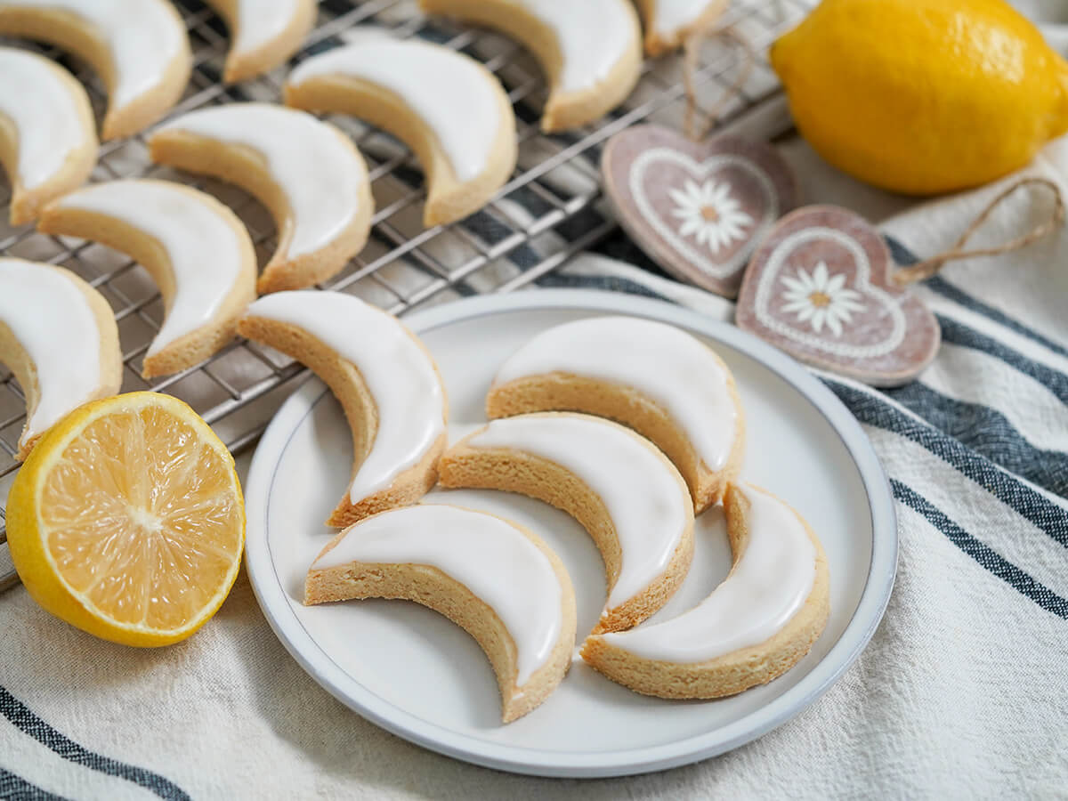 plate of lemon almond cookies zedernbrot with heart decorations behind and lemon to back and side.