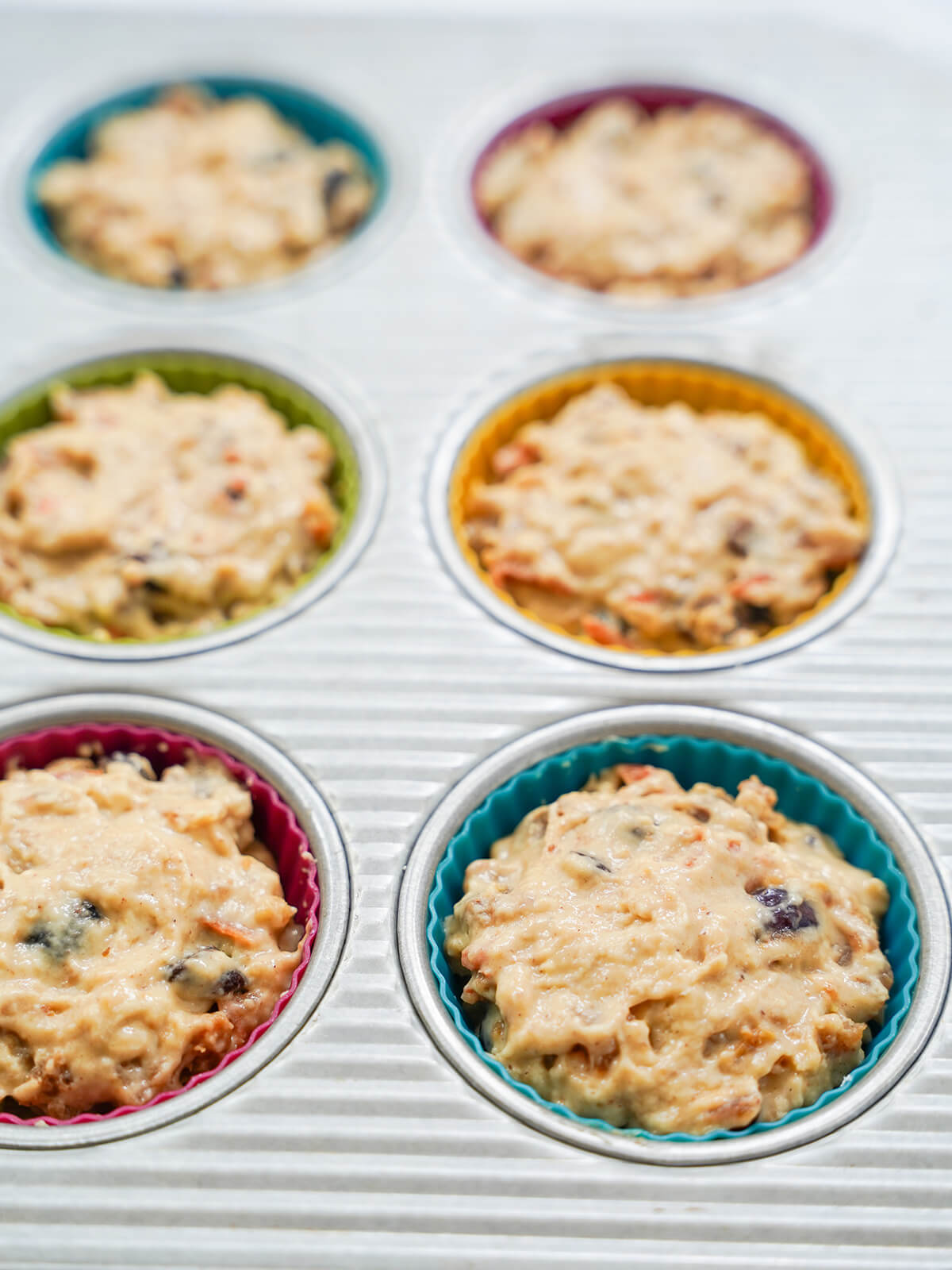 batter filling muffin liners in muffin tin.