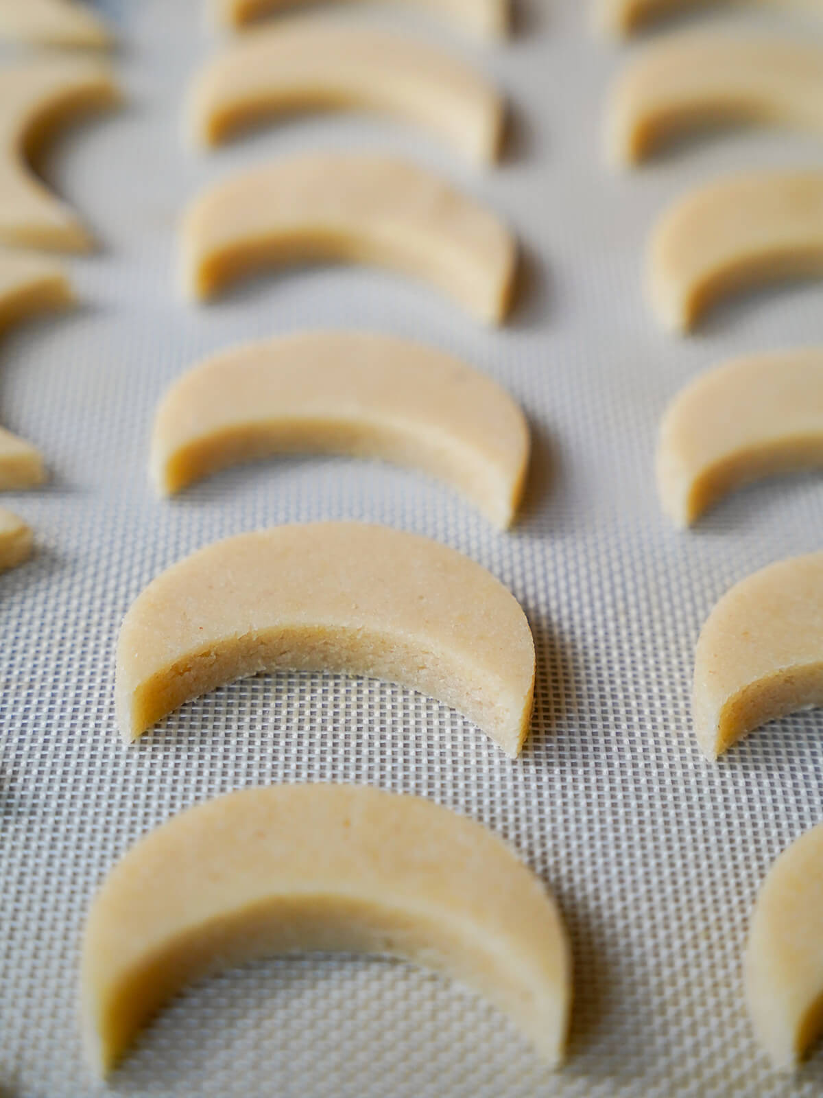 cut out moon shaped cookies on lined baking sheet before baking.