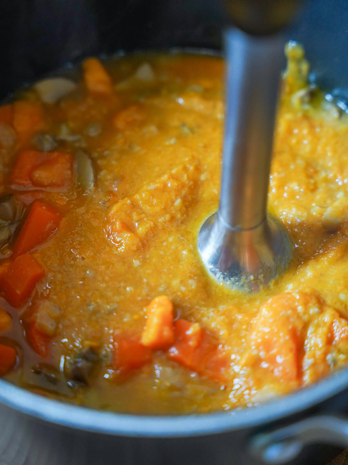 pot of soup with blender in blending up vegetables.