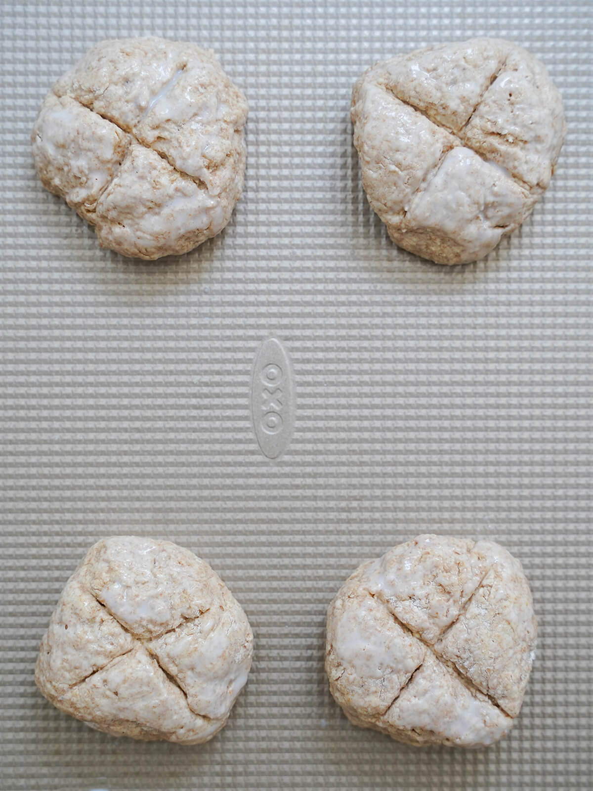 formed Irish soda bread rolls on baking sheet with cross cut on top of each one.