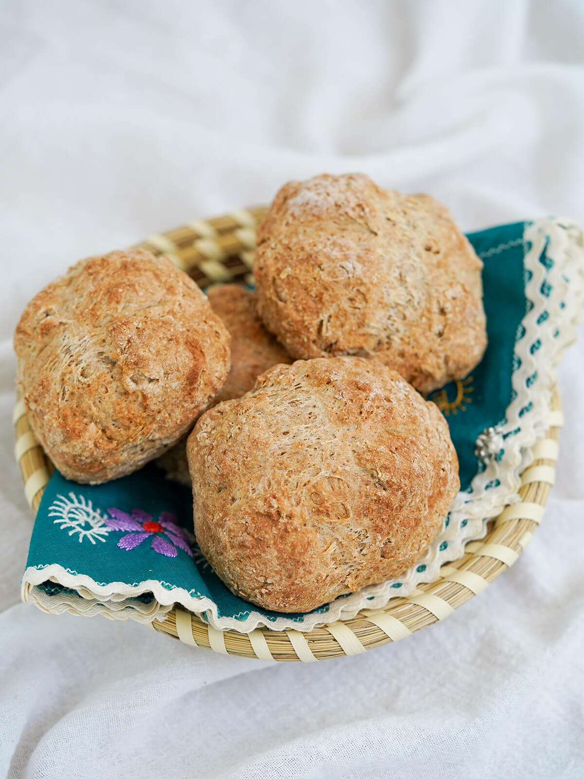 basket lined with green decorated cloth and filled with Irish soda bread rolls.