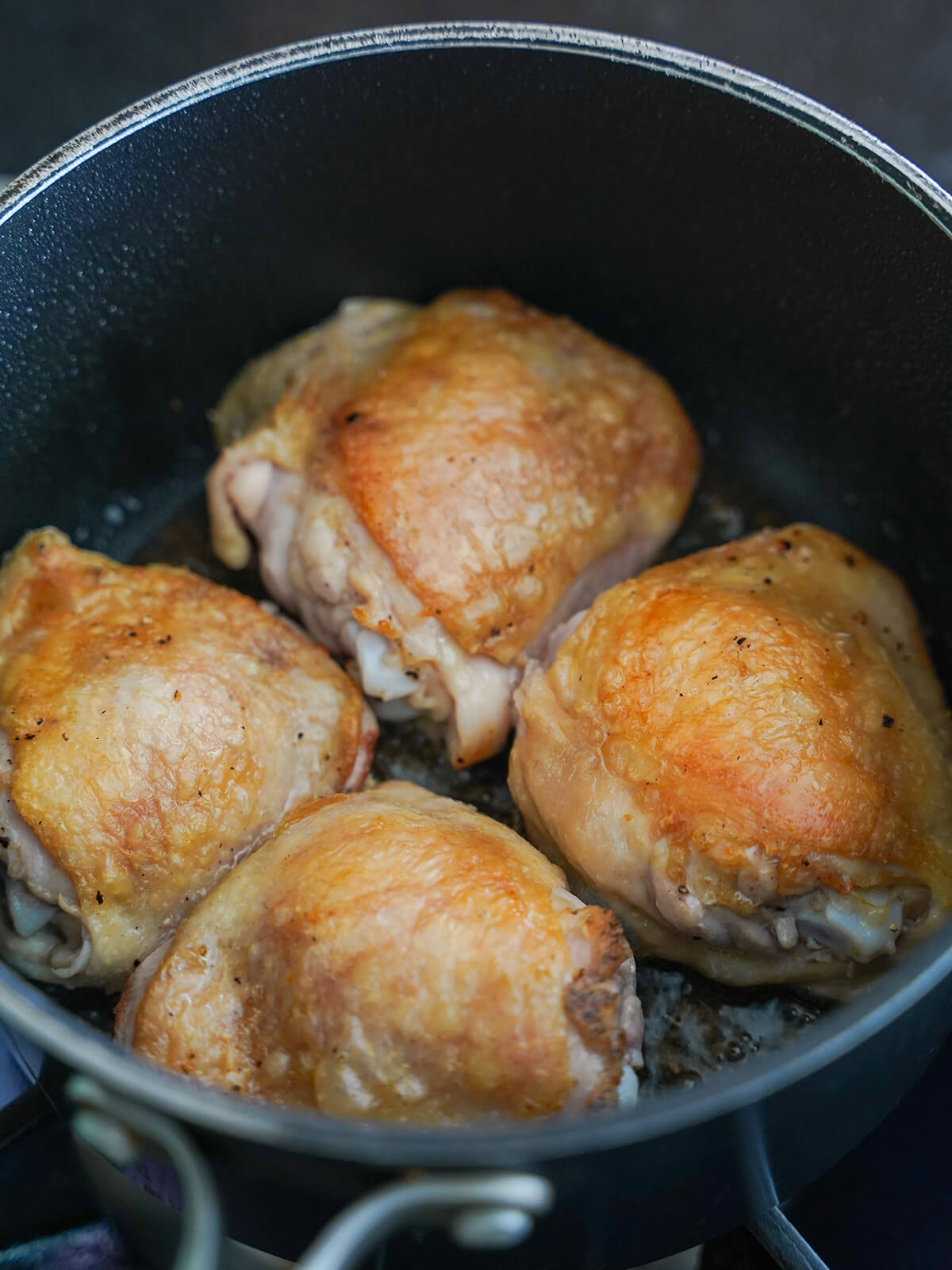chicken thigh with browned skin in pot.