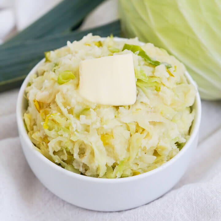 bowl of colcannon, mashed potatoes with cabbage, with pat of butter on top.