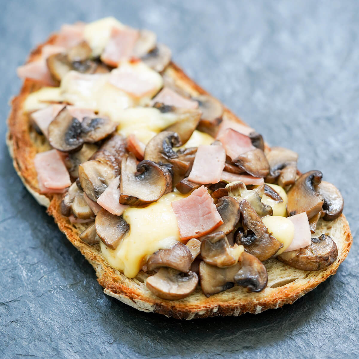 toast topped with mushrooms, ham and cheese, with cheese melting into rest.