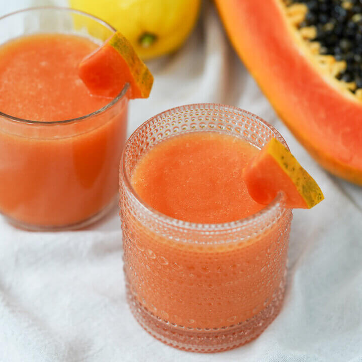 glasses of papaya lemonade garnished with small wedges of papaya.