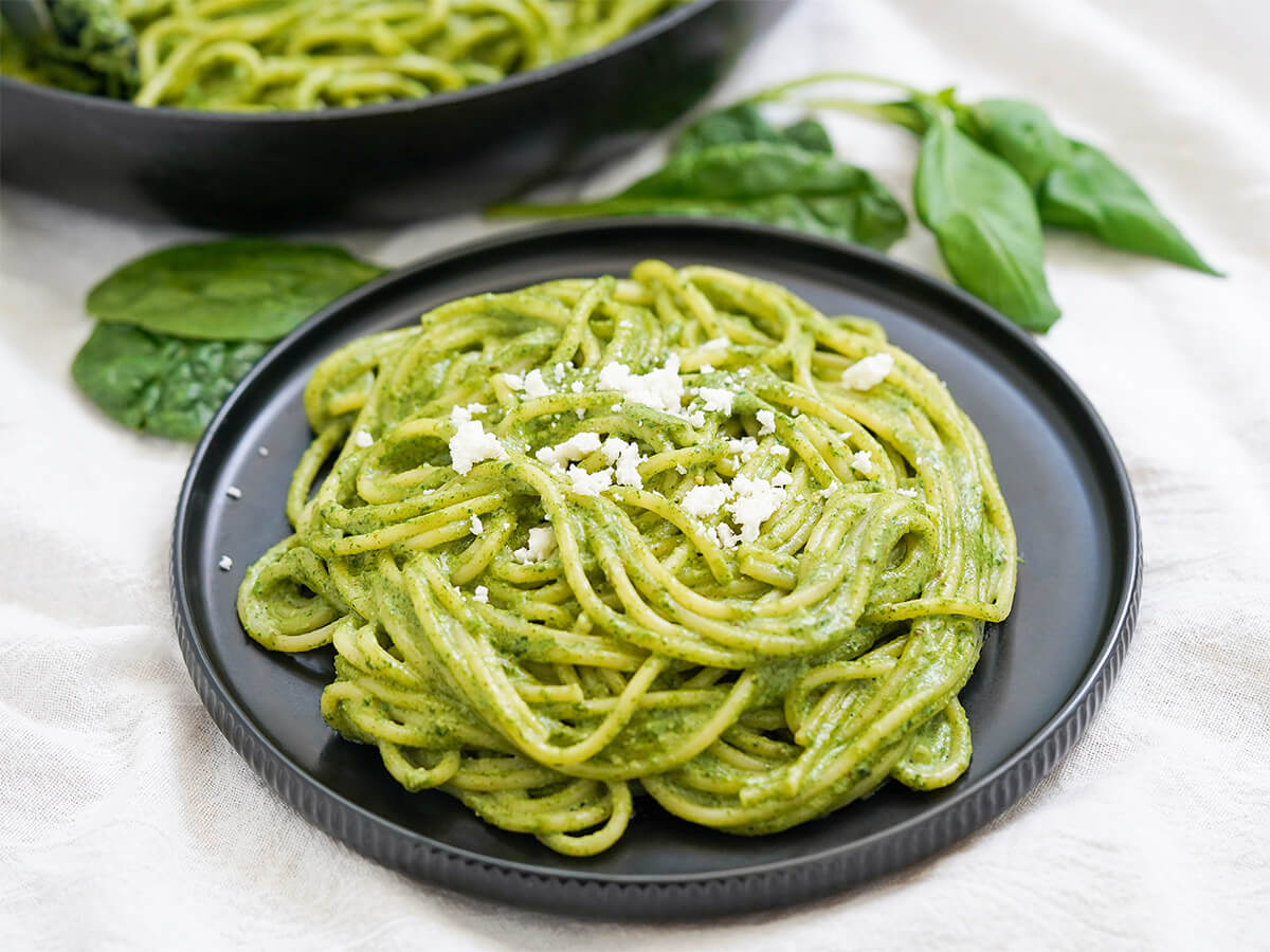 plate of tallarines verdes Peruvian pesto plate of tallarines verdes, pasta with Peruvian pesto, with spinach and basil leaves behind.