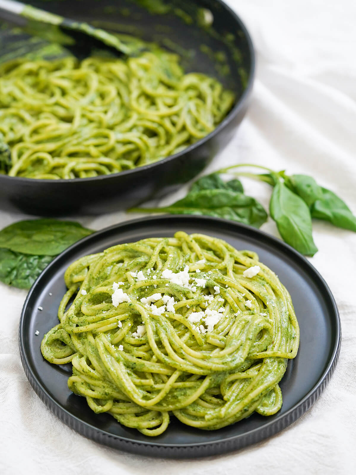 Tallarines verdes is Peruvian pesto that's that bit different from the classic, but no less tasty. Easy, creamy, smooth and comforting, it's great for busy nights or any excuse. plate of tallarines verdes, pasta with Peruvian pesto, with skillet with more behind.